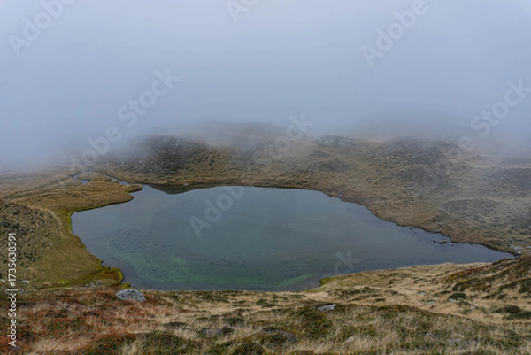 Fototapeta fog in the mountains and glacier lake on autumn moody day 