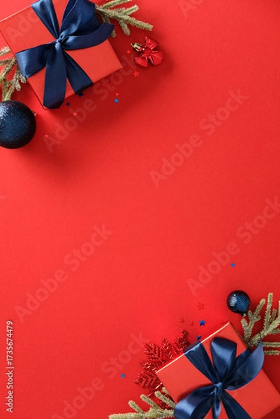 Fototapeta Christmas vertical banner, poster design. Top view red gift boxes with blue ribbons, baubles, fir branches on red background