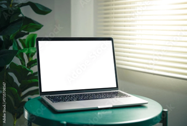 Fototapeta Laptop mockup with blank white screen on a green round table in window light. home office scene for UI previews, web banners, presentations, and product marketing.