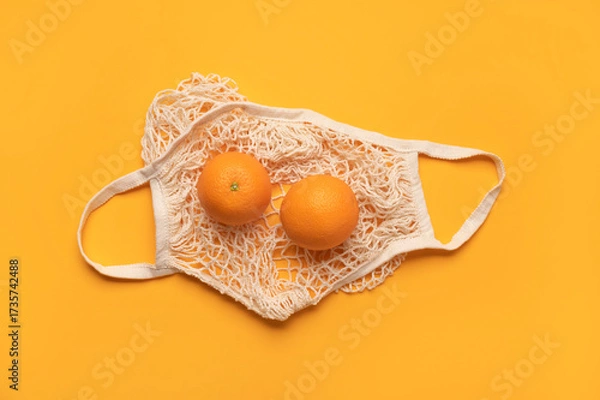 Fototapeta Eco-friendly thread bag for shopping, buying food, fruits, vegetables. Ripe juicy oranges in cotton string bag on yellow background top view flat lay. Zero waste, plastic free concept. Citrus fruits