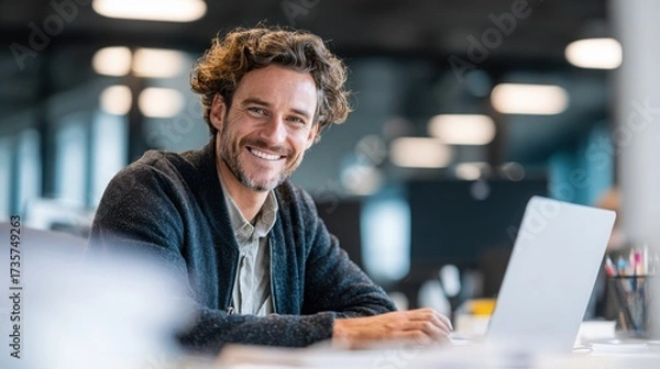 Fototapeta smiling young man working on a laptop in the office handsome, mature male businessman smiling while using his computer at his work desk.