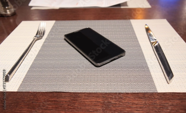 Fototapeta apkin on the table, a smartphone, a fork and a knife on it.