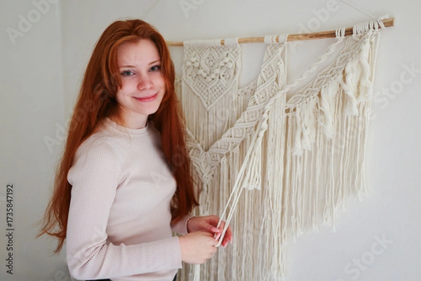 Fototapeta Girl with long red hair working on handmade macrame project.