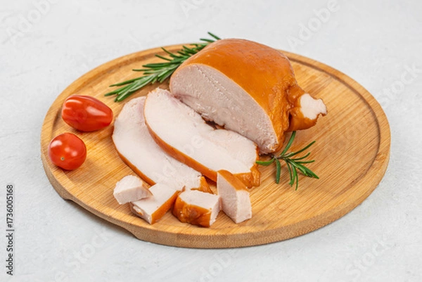 Fototapeta Juicy smoked chicken breast sliced and served on a wooden cutting board with rosemary and fresh tomatoes, delicious lean meat delicacy, rustic culinary presentation on light background