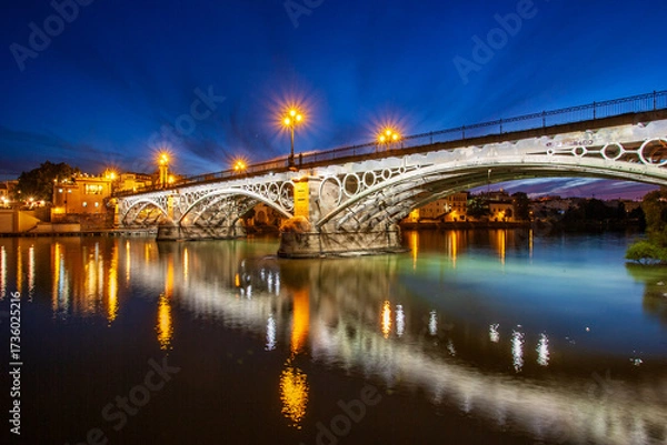 Obraz Dusk view of Triana Bridge in Seville with glowing street lamps
