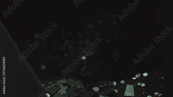 Fototapeta Small metal fragments and electronic parts glowing in scattered patterns over a dark surface, symbolizing technology, data, and digital processes within a manufacturing or industrial context