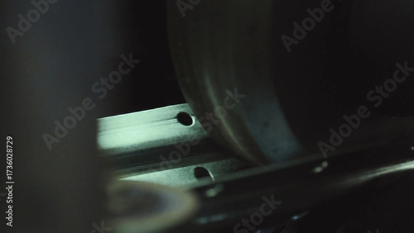 Fototapeta Industrial machine precisely forming or punching holes in a metallic steel strip, highlighting the detailed work and automated process within a manufacturing facility