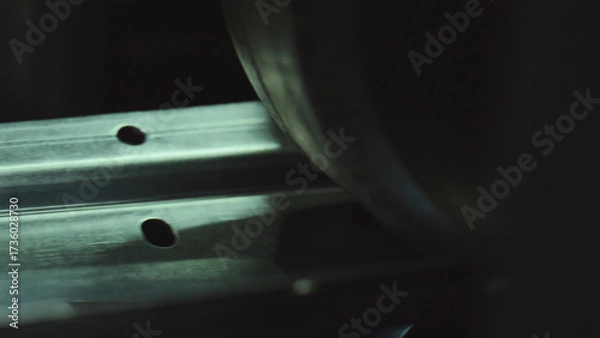 Fototapeta Steel channel with pre drilled holes running under a heavy roller, close up of precision metalworking and automated production in a modern industrial manufacturing setting