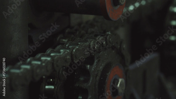 Fototapeta Dirty metal chain moving around a gear sprocket, suggesting mechanical power transmission and continuous movement within industrial processes and engineering