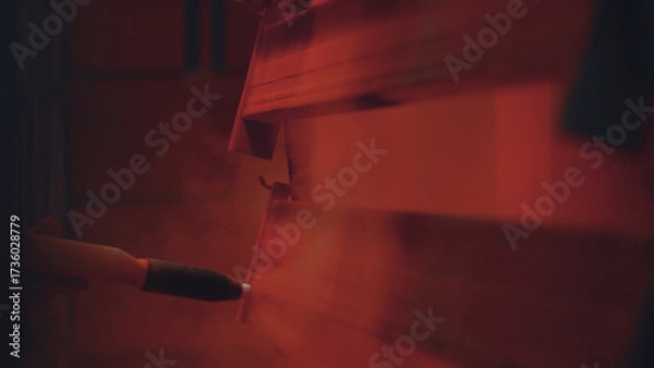 Fototapeta Powder coating gun applying paint to hanging metal profiles in an industrial setting, showcasing the modern process of surface finishing and protection in a manufacturing plant