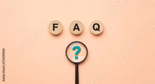 Fototapeta Magnifying glass focusing on a blue question mark below the letters FAQ displayed on three wooden circular blocks against a peach background