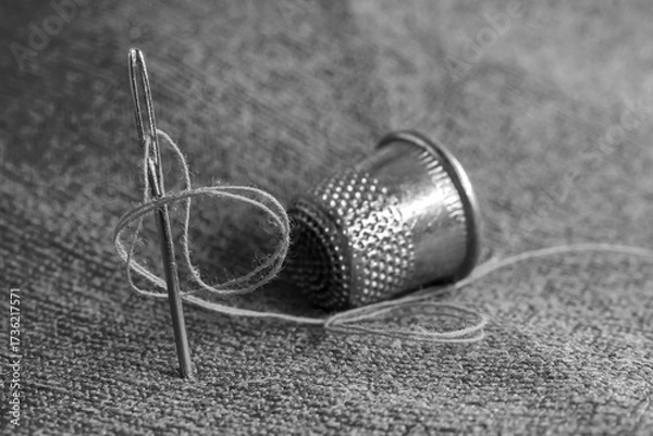 Fototapeta A needle and thread, a tape measure, and a thimble are lying on the fabric. Sewing supplies