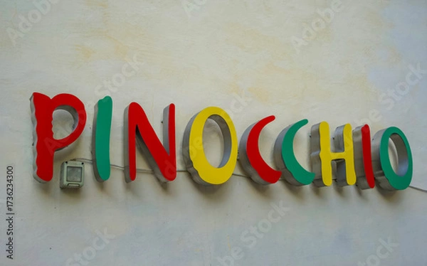 Fototapeta Colorful sign reading Pinocchio in vibrant letters against a textured wall creating a playful atmosphere