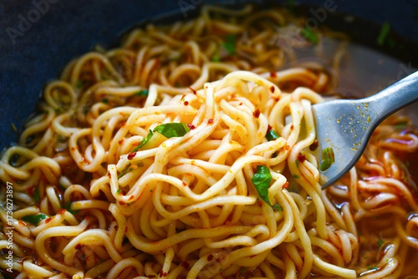 Fototapeta Instant noodles on fork in a bowl. Spicy noodle soup. Asian food style.