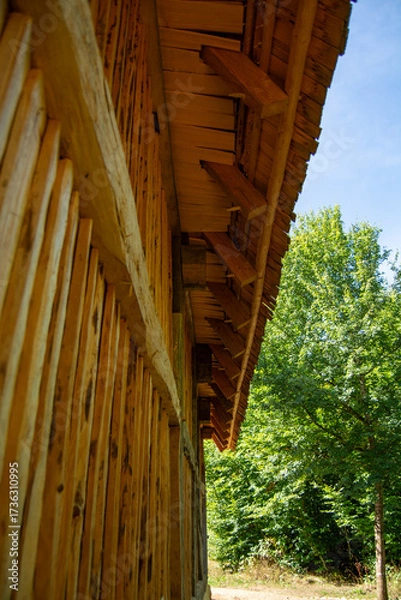 Fototapeta Wooden building with slanted roof and greenery