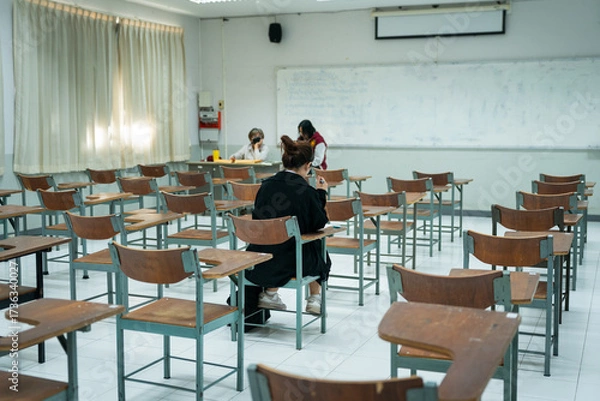 Fototapeta Last Student Completing Final Exam in Classroom