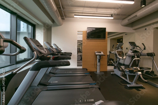 Fototapeta Workout area in gym with treadmills and cycling machines