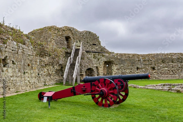 Obraz Old cannon with red carriage on grass inside Pevensey Castle ruins, East Sussex.