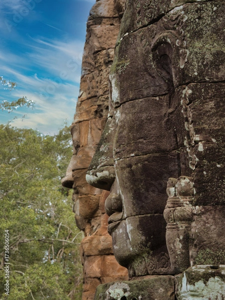 Obraz Khmer Smiling Stone Face - A close-up of a weathered, smiling stone face carving on a historic temple at Angkor, with detailed features and textures.