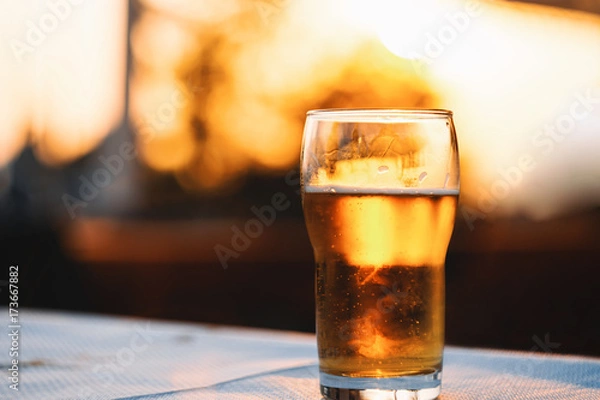 Fototapeta Refreshing Cold Lager Beer Laying On Table Against Sky During Sunset