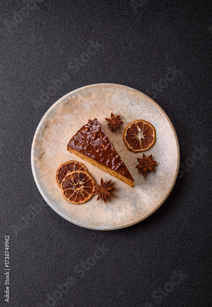 Fototapeta A slice of sweet layered cake covered in chocolate with nuts and caramel. A slice of chocolate cake