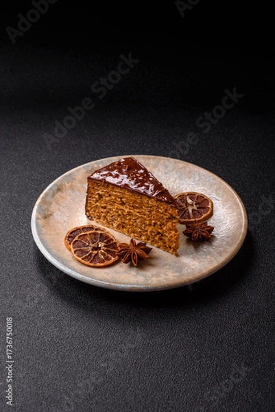 Fototapeta A slice of sweet layered cake covered in chocolate with nuts and caramel. A slice of chocolate cake