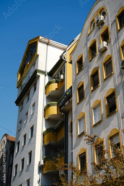 Obraz Residential building with yellow balconies and windows under blue sky in Novi Sad, Serbia.