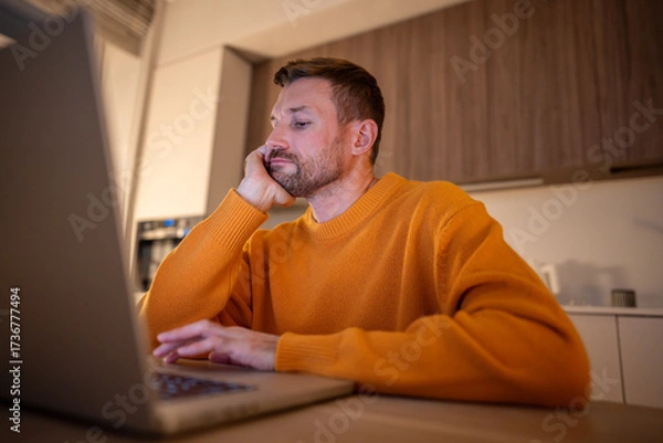 Fototapeta Man tired working on laptop, feeling exhaustion and boredom. Male meet deadlines, focus slip, long hours drain energy, persistent effort, mental strain, dedication despite overwhelming fatigue