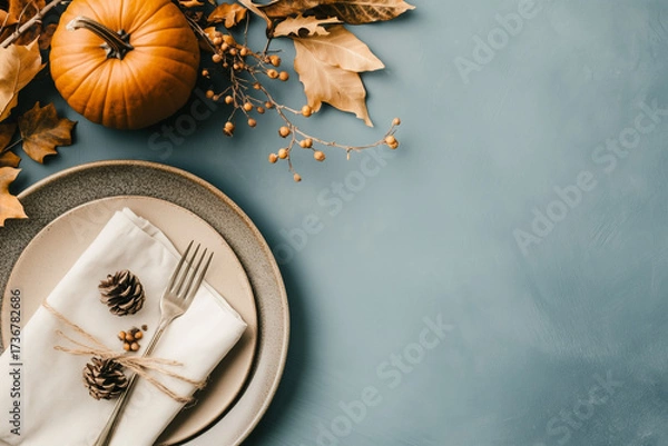 Fototapeta Top view of festive Thanksgiving table setting with pumpkin in plate, napkin and cutlery - autumn leaves decorated on blue background, flat lay