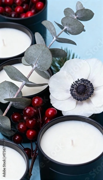 Fototapeta Elegant black candles with white anemone flower, eucalyptus leaves, and red berries on a light blue background
