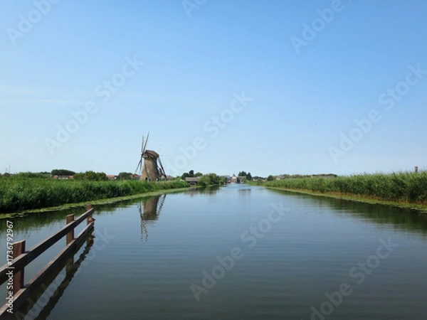 Fototapeta Traditional Windmill by a Canal on a Clear Summer Day