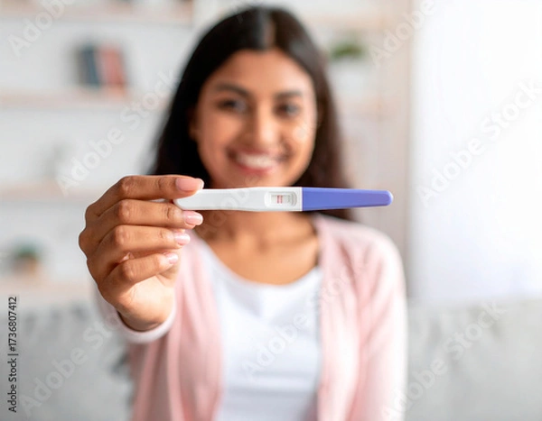 Fototapeta Emotional scene featuring a smiling person holding a pregnancy test.  The image conveys a moment of personal significance. Emotional storytelling, health and wellness theme, hopeful and joyful mood.