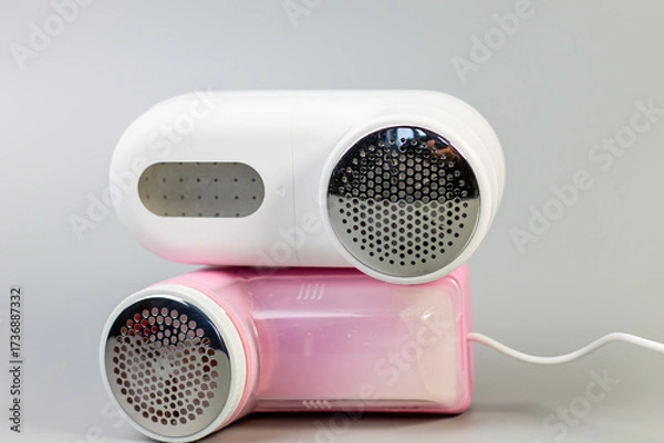 Fototapeta A stylish pair of electric fabric shavers in white and pink, stacked against a neutral grey background. The perfect tools for removing lint and pilling, keeping clothes looking their best.

