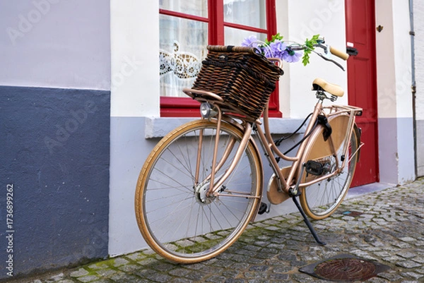 Fototapeta Bike with Basket Parked in Europe. A bicycle parked on a cobblestone street in front of a home in an old town in Europe.
