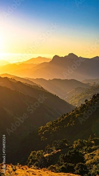 Obraz Sunlit Mountain Range Landscape with Golden Hues Layers of Hills Trees and Blue Sky Panoramic Vista in Warm Cinematic Light
