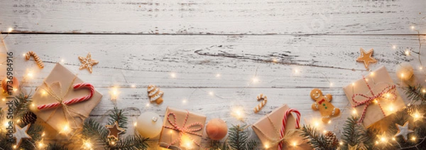 Fototapeta Paper Christmas gift box tied with twine and fir branch with glowing lights on wood background