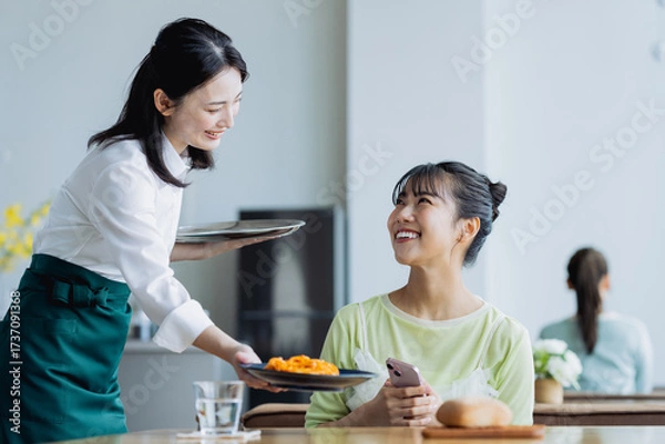 Fototapeta カフェで料理を配膳する若い女性