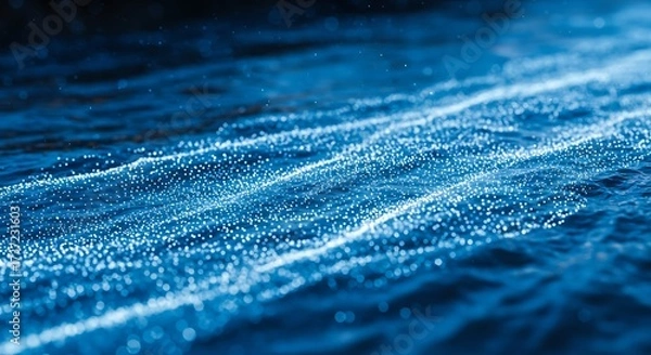 Fototapeta Bioluminescent plankton creating glowing trails on the surface of the ocean at night.