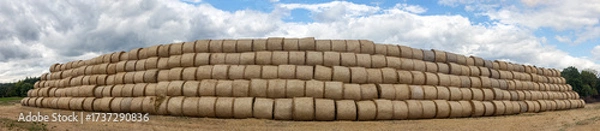 Fototapeta Large stack of hay bales arranged in a pyramid on a countryside landscape