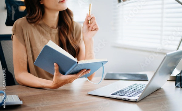 Fototapeta Closeup view of young professional businesswoman writing his idea concepts on notebook while working on his project at office