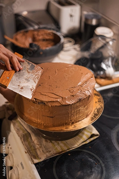Fototapeta Smoothing Chocolate Cake Frosting with Scraper Tool