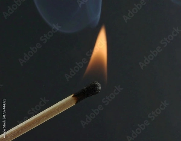 Obraz A lone match flame against a dark background glow