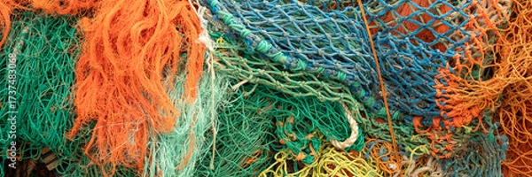 Fototapeta Panorama of pile of colourful fishing nets on a quayside for use as a background texture