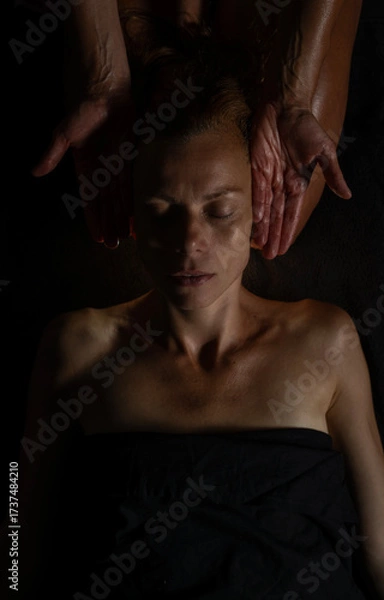 Obraz Close-up of female client receiving therapeutic shoulder massage. Moody lighting, warm tones, and soothing hands convey wellness and relaxation