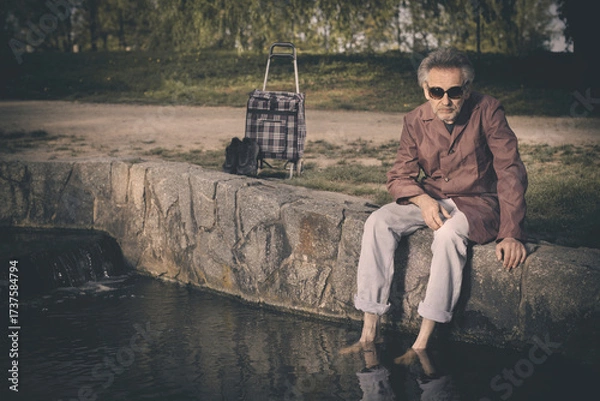 Fototapeta Senior citizen spending time alone in spring park with cart