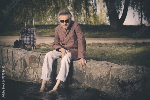 Fototapeta Senior citizen spending time alone in spring park with cart