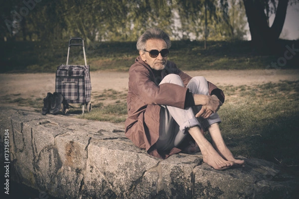Fototapeta Senior citizen spending time alone in spring park with cart