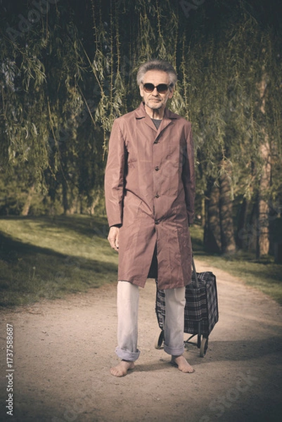 Fototapeta Senior citizen spending time alone in spring park with cart