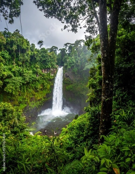 Fototapeta Hidden waterfall amid lush jungle and cliffside..