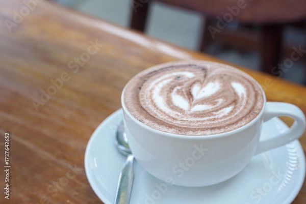 Obraz A cup of coffee with latte art on a wooden table